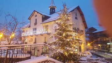 Un hôtel doté d’un balcon, dont le sol est recouvert de neige, et qui arbore un sapin de Noël illuminé.
