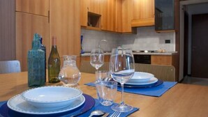 Une cuisine moderne avec des meubles en bois, un four encastré et une table à manger dressée avec des assiettes et des verres.