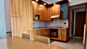 Une cuisine moderne avec des meubles en bois, une cuisinière encastrée et un coin repas comprenant une table et des chaises.