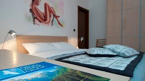 Une chambre à coucher avec un lit, une table de chevet, une lampe, un tableau au mur et une porte.