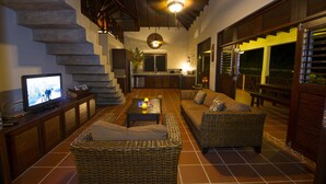 A spacious living area with wicker furniture, a television, and a staircase. - Upper Level apartment overlooking Marigot Bay (Marigot bay)