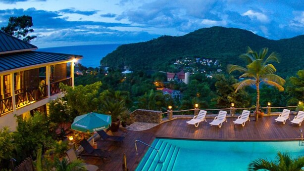 A resort with a pool, lounge chairs, and a view of the ocean and hills. - Upper Level apartment overlooking Marigot Bay (Marigot bay)