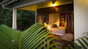 A bedroom with a bed, a nightstand, and a window with shutters. - Upper Level apartment overlooking Marigot Bay (Marigot bay)