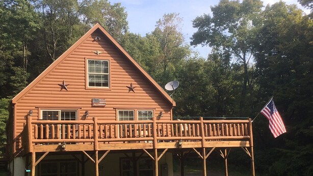 A wooden cabin with a balcony, an American flag, and a satellite dish. - All Star Acres 2 Miles To Park
5 BR,3 baths
 Dates align with Dreams Park ONLY! (Milford)