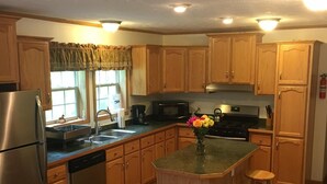 A kitchen with wooden cabinets, a stainless steel refrigerator, a microwave, a stove, and a sink. There are two wooden stools at the island. - All Star Acres 2 Miles To Park
5 BR,3 baths
 Dates align with Dreams Park ONLY! (Milford)