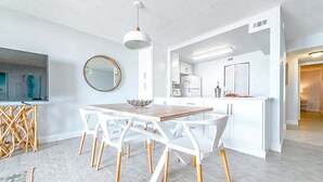 Eine moderne Küche mit weißen Schränken, einem Holzespeisetisch und weißen Stühlen.