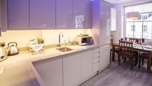 Eine moderne Küche mit weißen Schränken, einer eingebauten Mikrowelle und einem Essbereich mit Holztischen und einem Tisch.