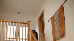 A wooden staircase with a bench at the bottom, a door leading to another room, and a wall with a patterned tapestry. - Beautiful Holiday Cottage, Dunfanaghy, Donegal (Dunfanaghy)