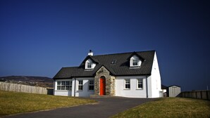 A two-story house with a red door, white walls, and a stone facade. - Beautiful Holiday Cottage, Dunfanaghy, Donegal (Dunfanaghy)