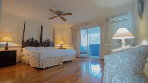 Ein Schlafzimmer mit zwei Betten, einem Deckenventilator und einem Balkon mit Blick.