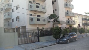 Un edificio residencial de varios pisos con balcones, una entrada con portón y un coche estacionado en la calle.