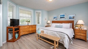 Ein Schlafzimmer mit Bett, Nachttischen, einem Fernsehschrank und einer Bank.