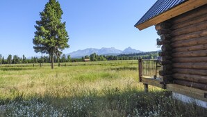 A log cabin with a wooden deck and a mountain view.