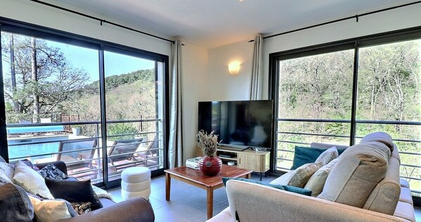 Un salón espacioso con ventanas amplias, televisor de pantalla plana y vistas a la piscina.
