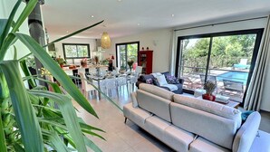 A modern living room with a sofa, dining table, and chairs. There is a large window with a view of the outdoors. - House / Villa - Aubenas (Aubenas)