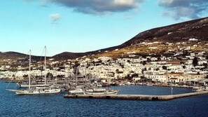 Experience the charm of a coastal town with a bustling marina and picturesque hills in the background.