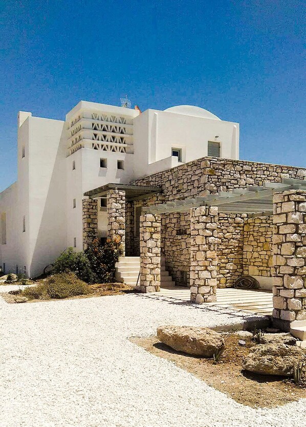 A white building with a stone staircase leading to a covered entrance. - Villa Mella, Glyfa Beach Paros: luxury vacations by the sea, panoramic view (Glyfa Beach)