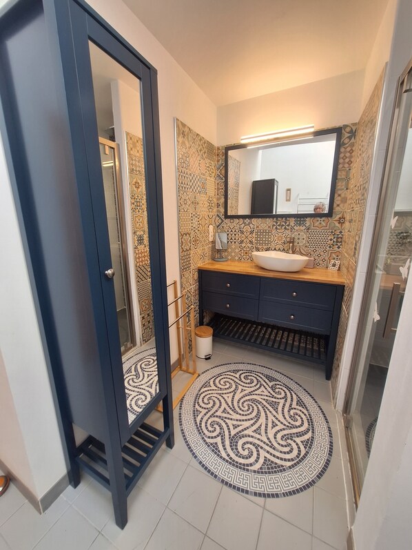 A bathroom with a round mosaic floor, a sink with a mirror above it, and a dark-colored cabinet. - House / Villa - Batz sur Mer (Batz sur Mer)