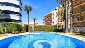 A swimming pool with a circular design, surrounded by buildings and palm trees.