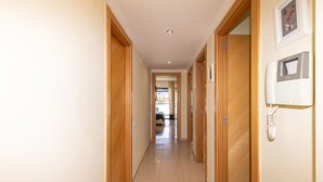 A hallway with wooden doors, a light switch, and a framed picture on the wall.