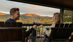 A couple toasting with wine glasses at a table with a scenic view of mountains and autumn foliage. - Romantic Couples Log Cabin #4 Hot Tub and Breathtaking Mountain Views near LURAY (Luray)