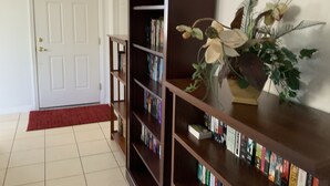 A hallway with a white door, a red carpet, and a bookshelf with books and a potted plant. - Spacious, LUXURY 4 bedroom villa with pool and spa close to Disney (Haines City)