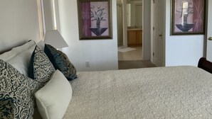A hotel room with a large bed, a bedside lamp, patterned pillows, and two framed artworks on the walls. - Spacious, LUXURY 4 bedroom villa with pool and spa close to Disney (Haines City)