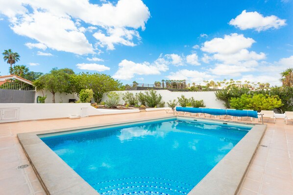 A rectangular swimming pool with a tiled edge, surrounded by a tiled deck.