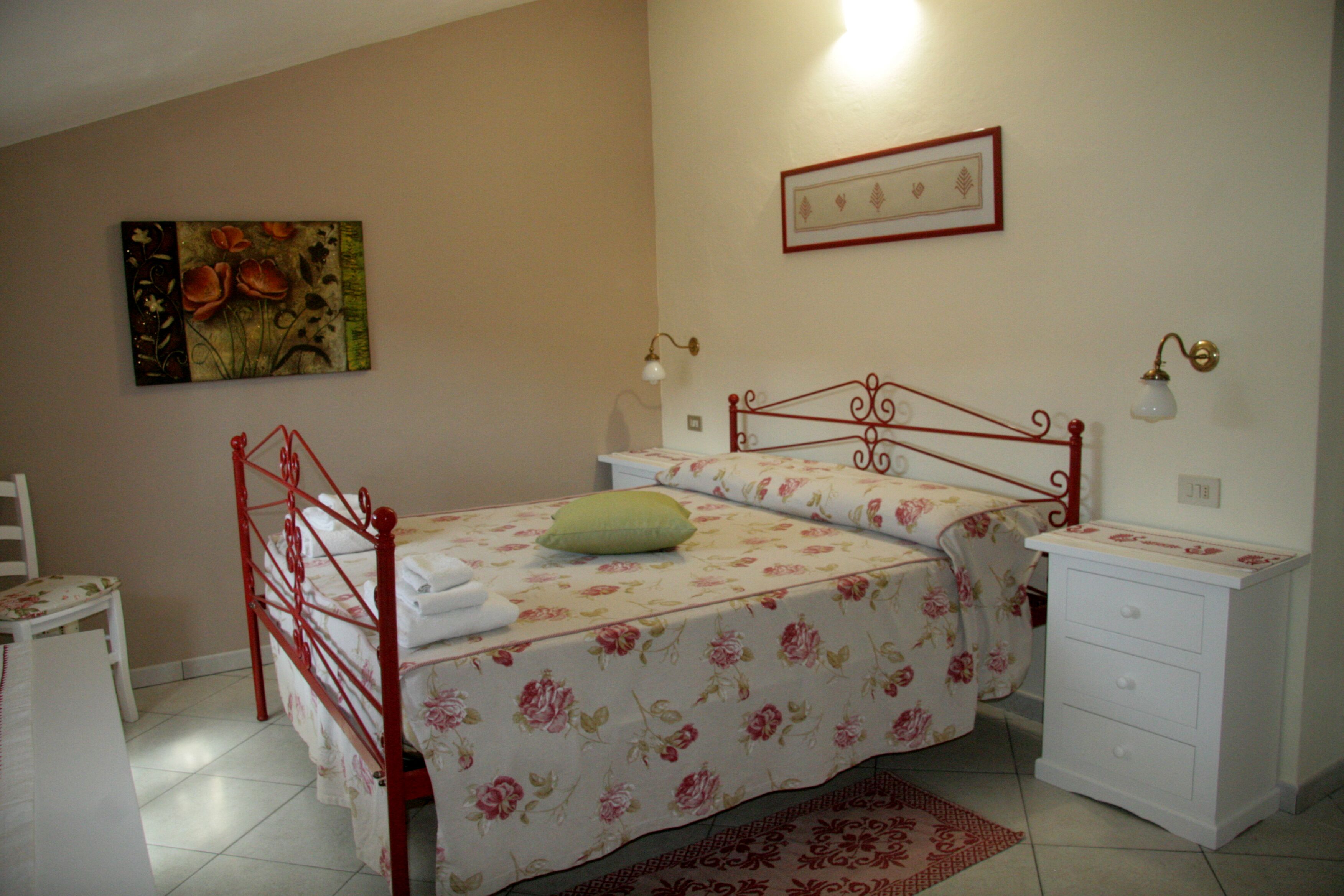Une chambre à coucher avec un lit, une table de chevet, une chaise et un tableau accroché au mur.