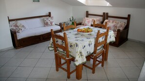 A dining area with a table set for four, surrounded by wooden chairs, a sofa with floral cushions, and a small vase with flowers. - Apartment/ flat - Teulada (Teulada)