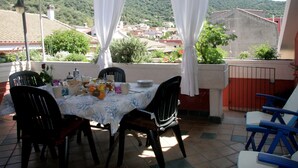 A balcony with a table set for a meal, surrounded by chairs, overlooking a town with buildings and greenery. - Apartment/ flat - Teulada (Teulada)