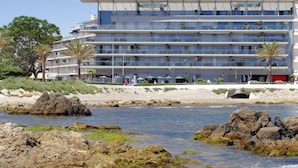 Un hôtel moderne à plusieurs étages, situé en bord de mer, avec une côte rocheuse.
