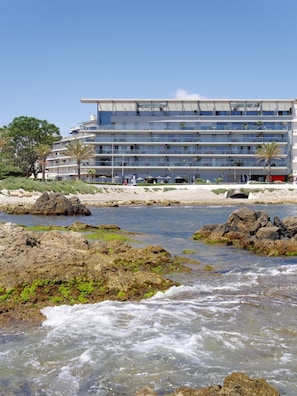 Een modern hotel met meerdere verdiepingen, een ligging aan het strand en een rotsachtige kustlijn.