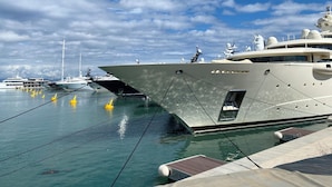 Un port de plaisance où sont amarrés plusieurs yachts, avec un ciel dégagé et une eau calme.
