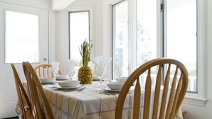 Een eethoek met een tafel voor vier personen, houten stoelen en een ananas als middelpunt.