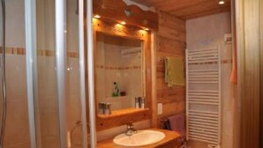 Een badkamer met een houten wastafelmeubel, een wastafel, een spiegel en een handdoekhouder.