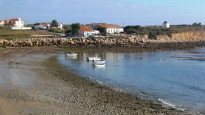 Una zona costera con un litoral rocoso, varios barcos y edificios al fondo.