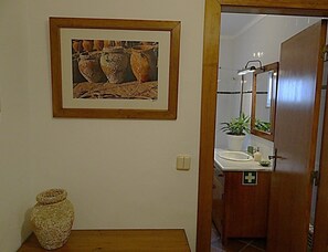 A bathroom with a sink, mirror, and a framed picture on the wall. - CASA SÃO JOÃO T1 - 1 bedroom apartment 100 m from the beach (Peniche)
