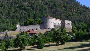 A historic stone building with a red roof, surrounded by trees and hills. - Spacious apartment with large terrace in nature (Allos)