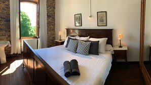 A neatly made bed with pillows, a wooden headboard, and a nightstand with a lamp. - Enjoy your holiday in a former school in the French Limousin (Troche)