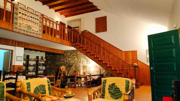 Ein geräumiges Wohnzimmer mit einer Holztreppe, einer Steinwand und einer grünen Tür.
