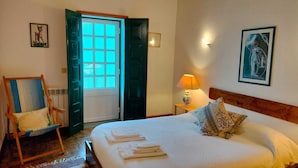 Ein Schlafzimmer mit einem Bett, einem Sessel, einer Lampe und einer Tür mit Fenster.
