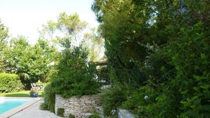 A stone wall with a pool and lush greenery. - Charming villa with swimming pool, Avignon, 6 people, large Mediterranean garden (Villeneuve-Lès-Avignon)