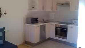A compact kitchen with white cabinets, a microwave, a toaster, and a dishwasher. - Vacation apartment in Hochkönig, hiking possibilities just in front of the door (Mühlbach/Hochkönig)