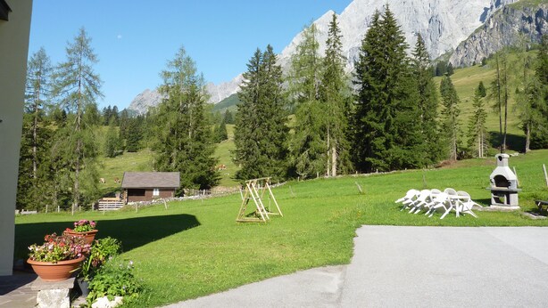 A mountain view with a wooden structure, a grassy area, and a stone bench. - Vacation apartment in Hochkönig, hiking possibilities just in front of the door (Mühlbach/Hochkönig)