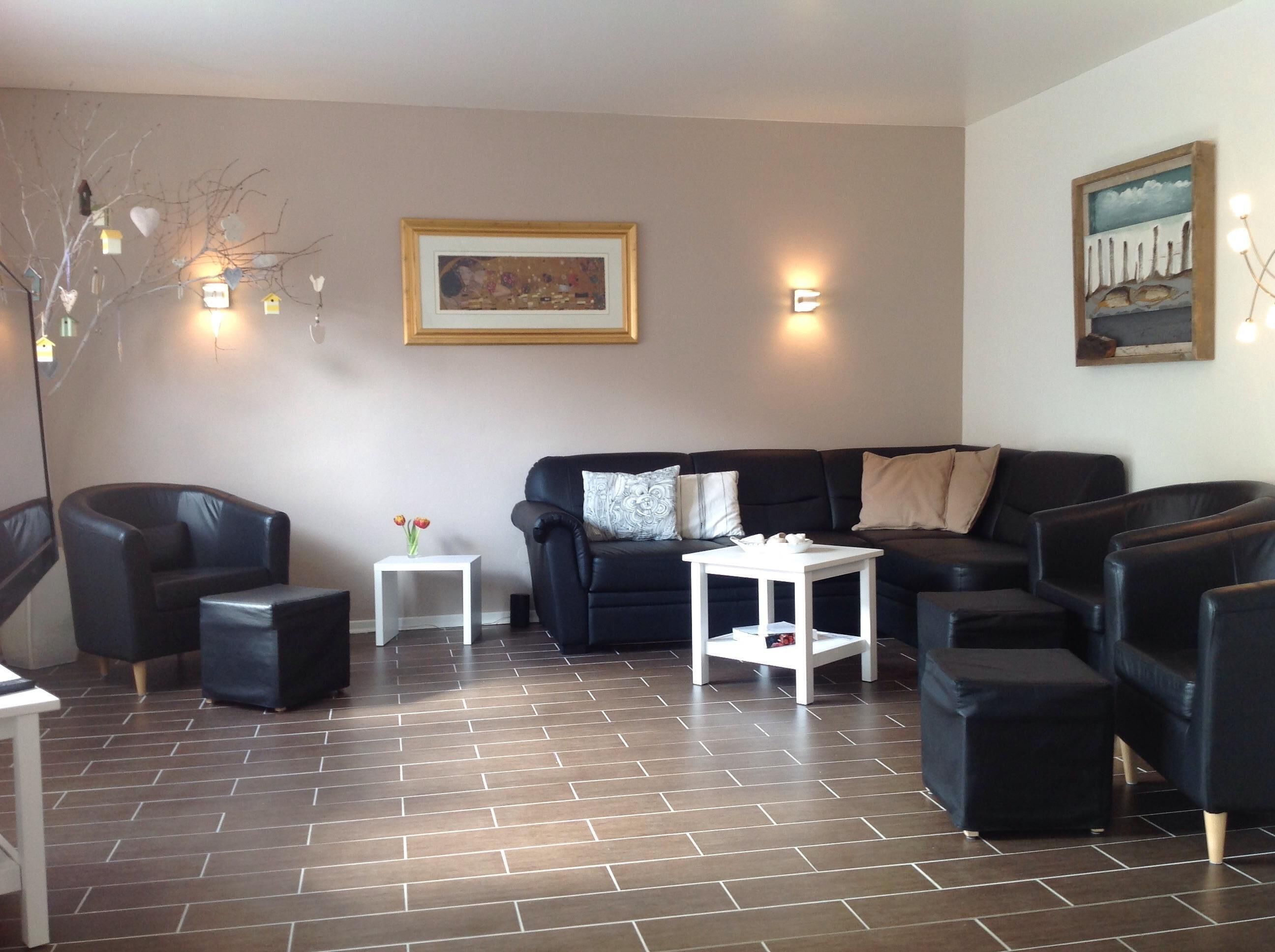 Ein modernes Wohnzimmer mit einem schwarzen Ledersofa, einem weißen Beistelltisch und einem schwarzen Sessel.