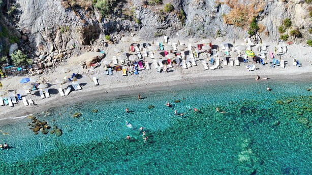 Une plage avec une eau claire, des chaises longues et des parasols.