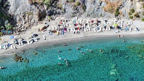 Una playa con agua cristalina, tumbonas y sombrillas.
