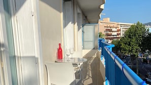 Ein Balkon mit Tisch, Stühlen, einer roten Flasche und zwei Gläsern.