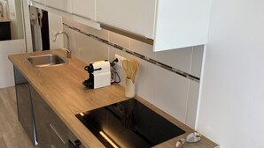 Eine moderne Küche mit weißen Schränken, einer Holz Arbeitsplatte, einer schwarzen Induktionskochplatte und Edelstahlgeräten.